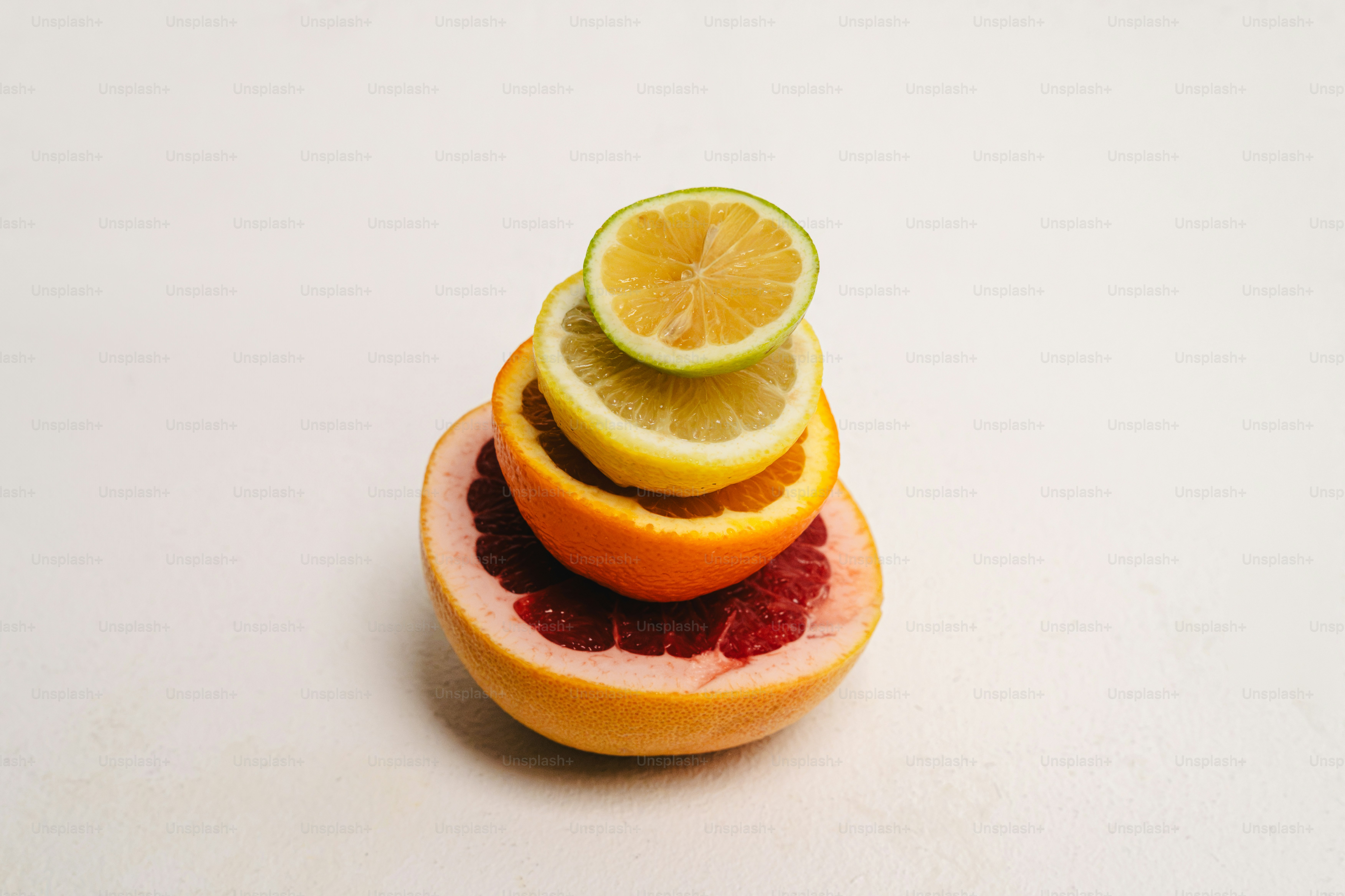 Citrus fruit slices stacked on white - Photo on Unsplash+