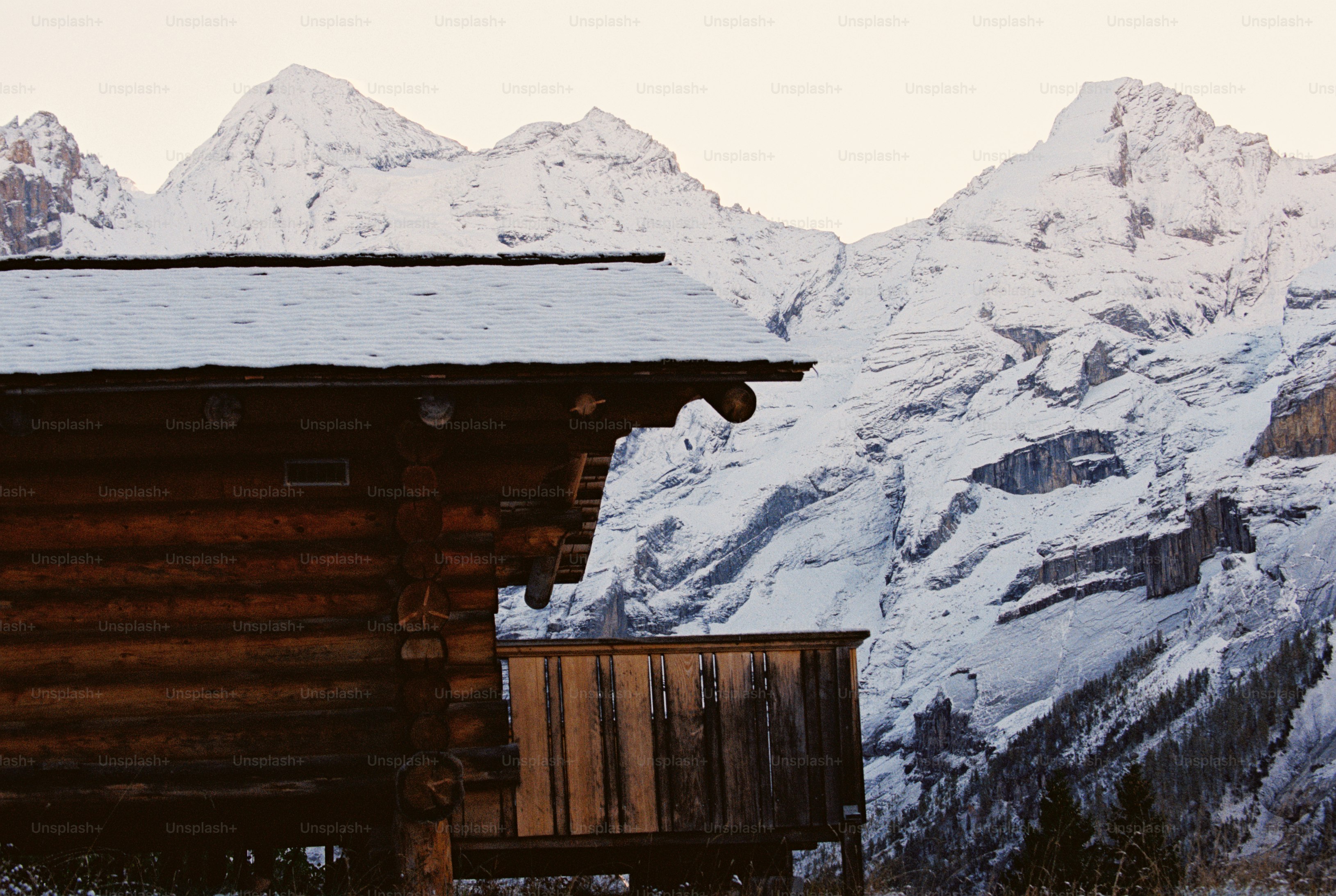Snowy chalet roof and mountain peaks - Photo on Unsplash+