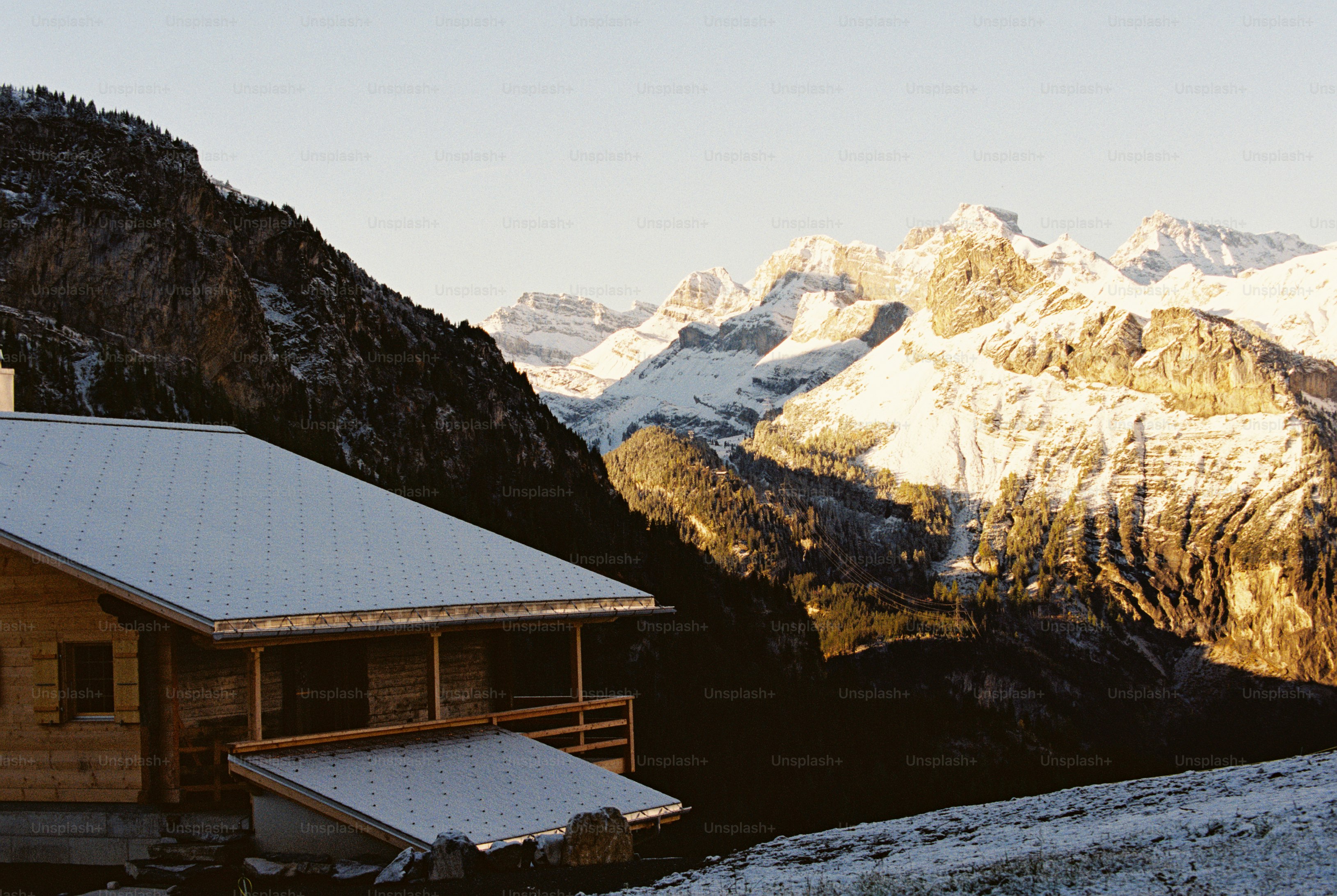 Snowy chalet roof and mountain peaks - Photo on Unsplash+