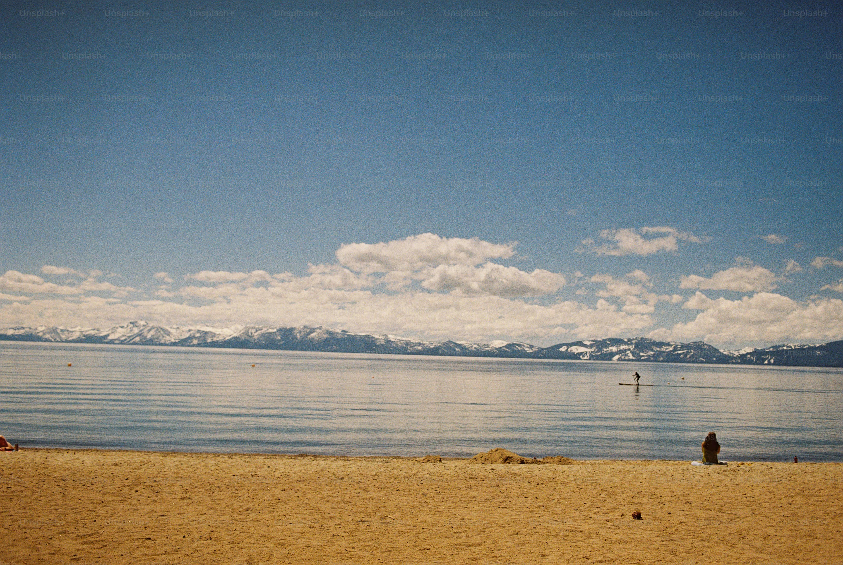 Paddleboarder on lake with snowy mountains - Photo on Unsplash+