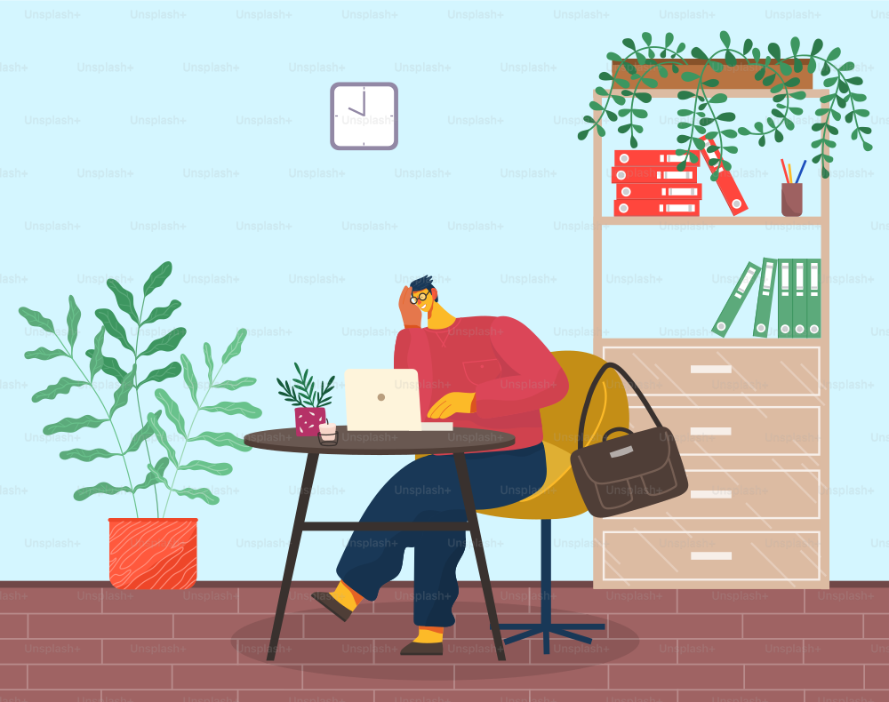 Young pensive man in glasses and red sweater sits, propping face on hand. Yellow armchair, coffee table, laptop, plant, candle. Office cabinet, folders, stationery, climbing plant. Tired man at laptop