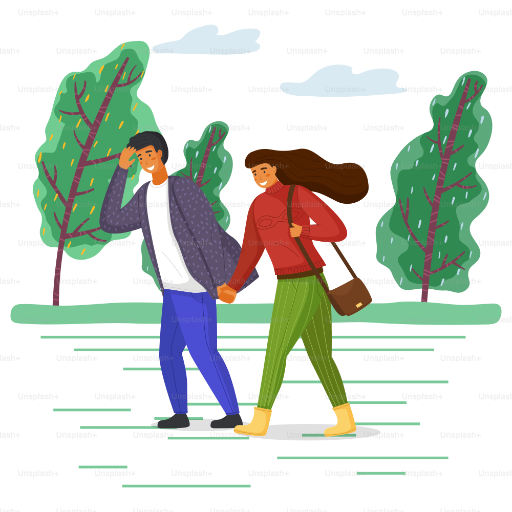 Woman and man in casual clothes walk in the park on the road in windy weather, girl hair fluttering in the wind. Strong wind blows, trees bend to the ground, young people smiling holding hands