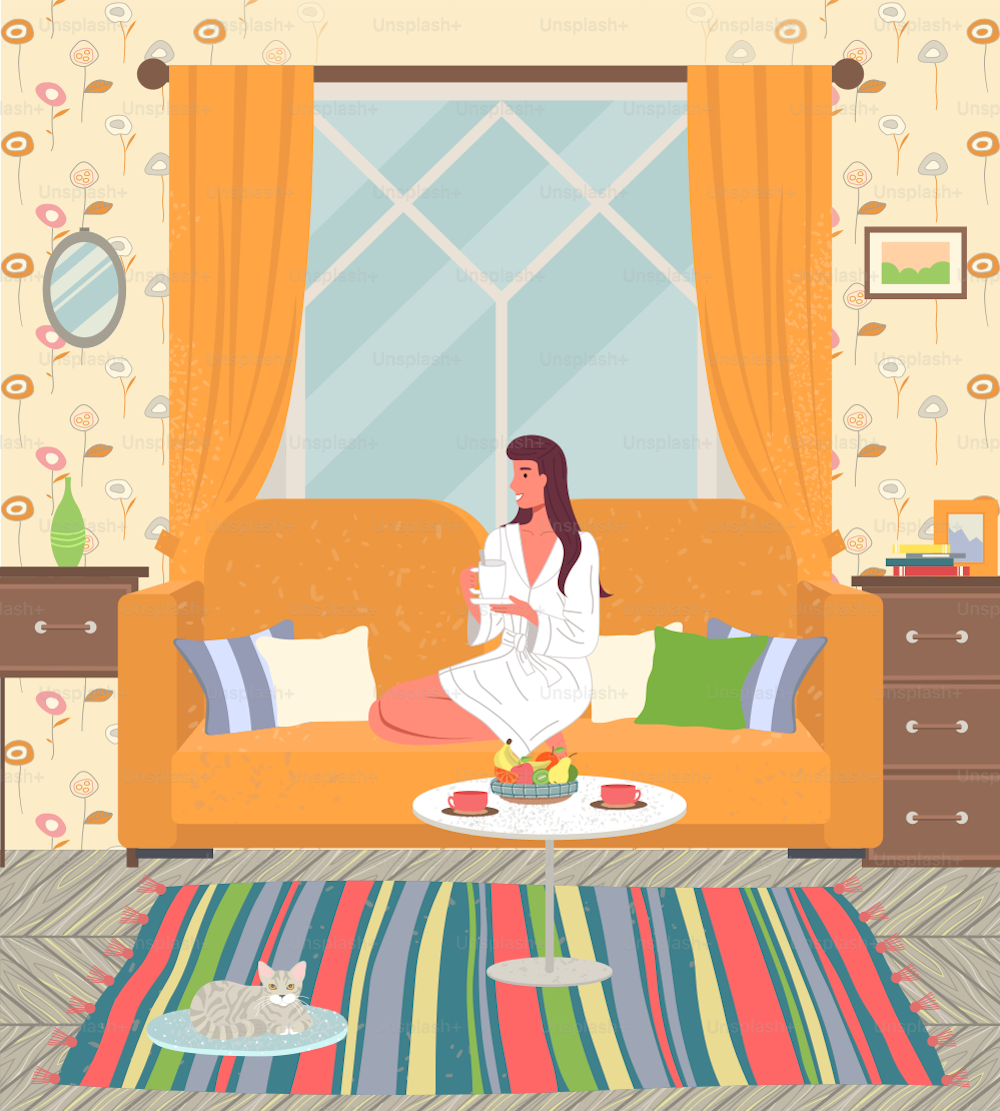 Cozy home interior of the living room. Young girl in white coat is sitting on yellow sofa with cup of tea. Decorative couch pillow. Cupboards, cat on rug. Mirror on the wall, striped rug. Rest at home