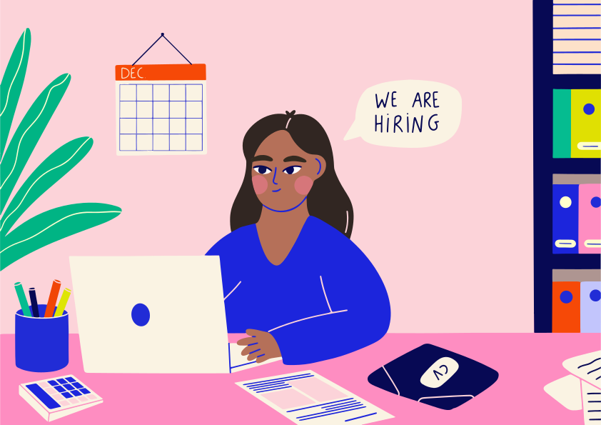 Woman working at desk with 'we are hiring' sign.