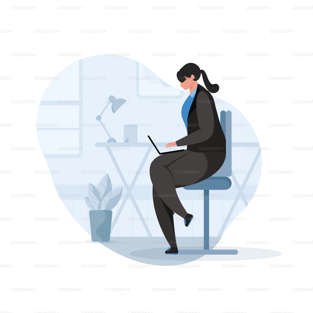 Woman in suit working on laptop at desk.