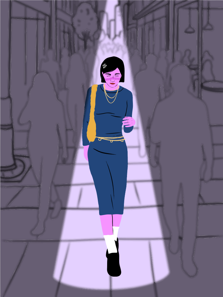 Mujer caminando bajo un foco en una calle de la ciudad.