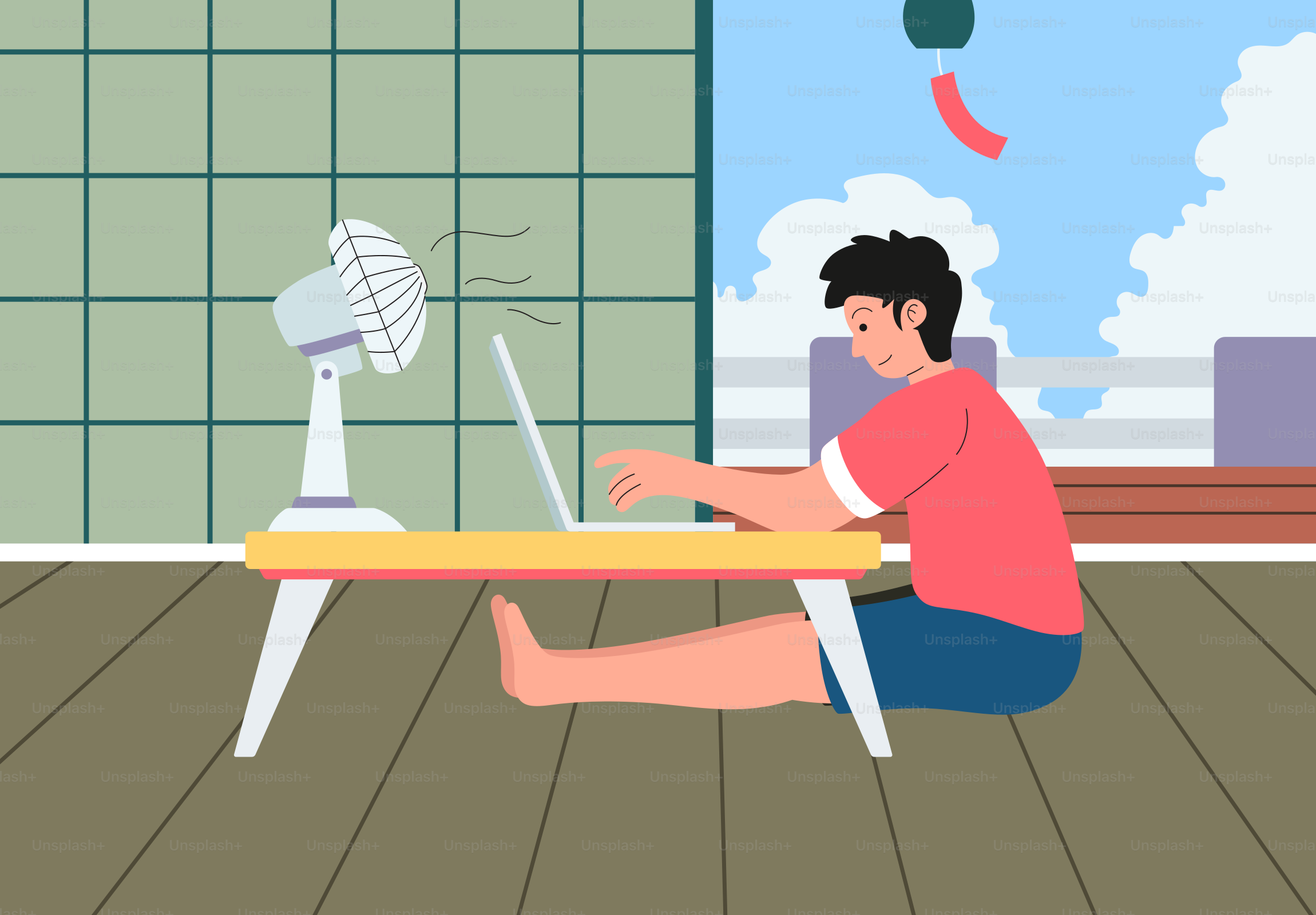 Man working on laptop with fan on floor.