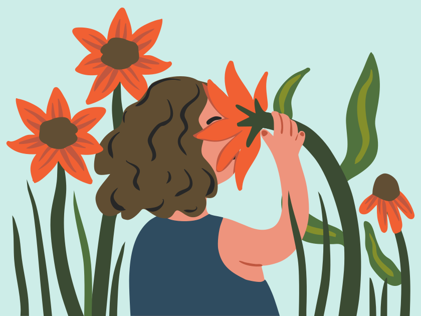 Une personne sentant une fleur d’oranger parmi de grandes plantes.