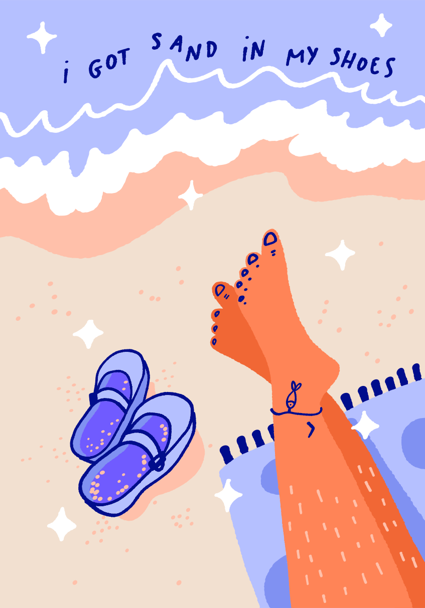 Feet and sandals on a sandy beach near ocean waves.