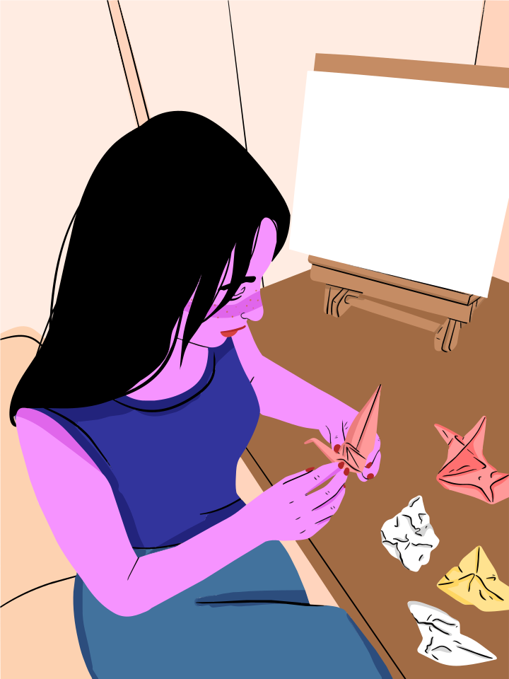 女性がイーゼルを置いたテーブルで折り紙を折っている。